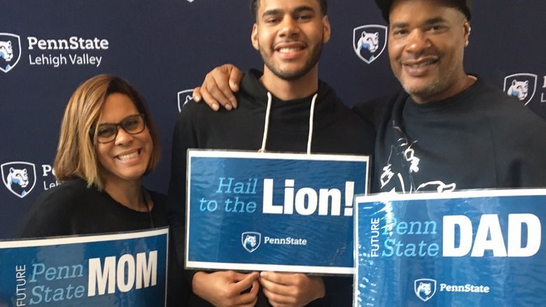 Young man posing with his parents and PSU-LV signs