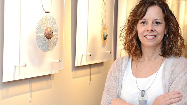 woman smiling in art gallery next to pieces of art