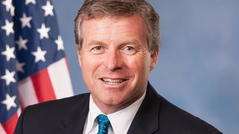 head shot of man in front of american flag