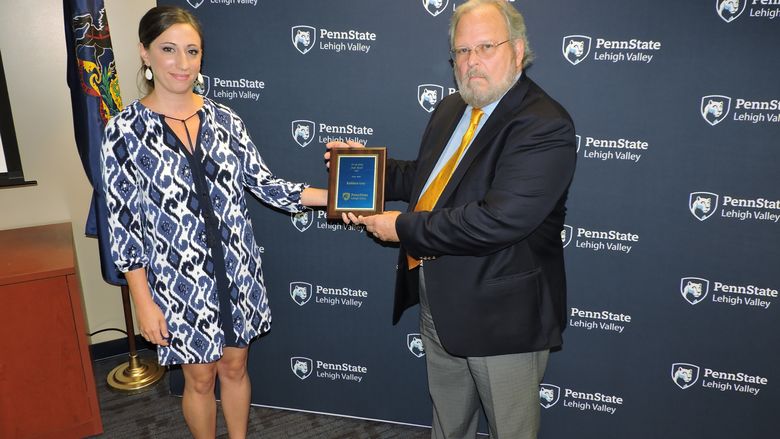 two people leave a space for award winner who has passed