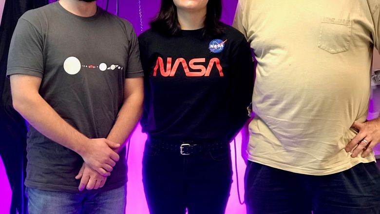 three people in front of bright purple lights