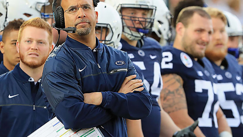 Coach Franklin standing on sidelines looking up with headset on
