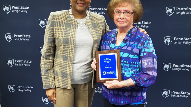 a woman handing a professor a plaque