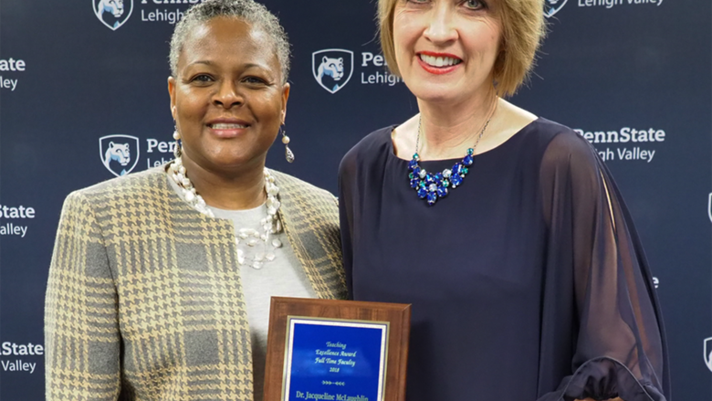 a woman handing a professor a plaque