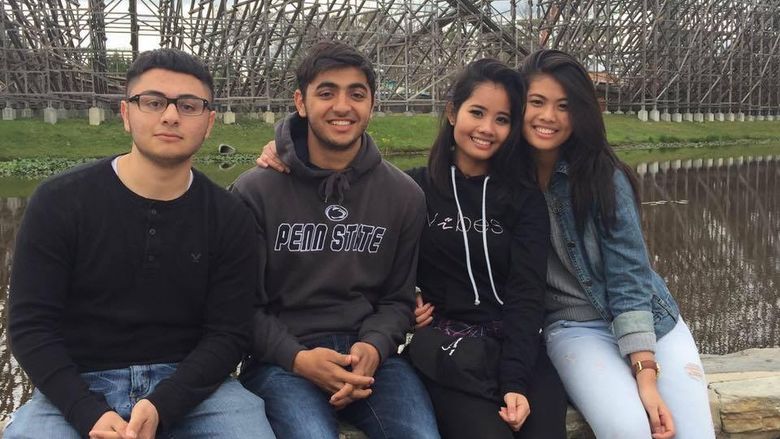 A group of students sit in front of a roller coaster