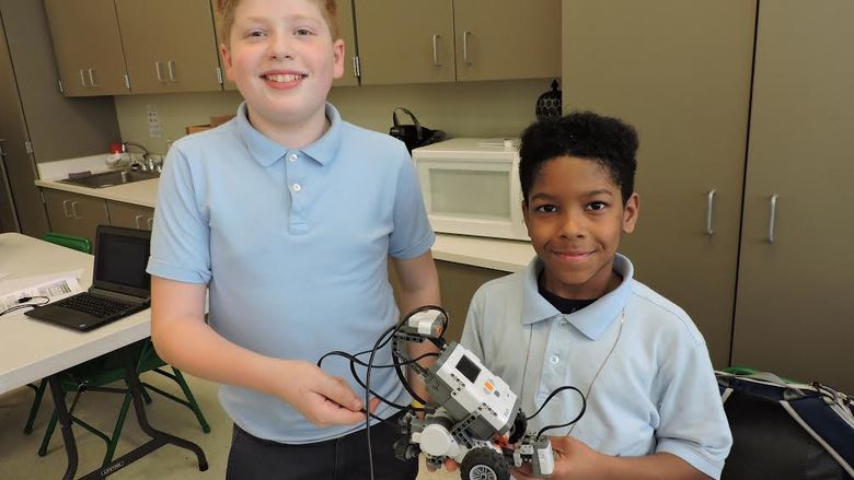 two students holding robotics