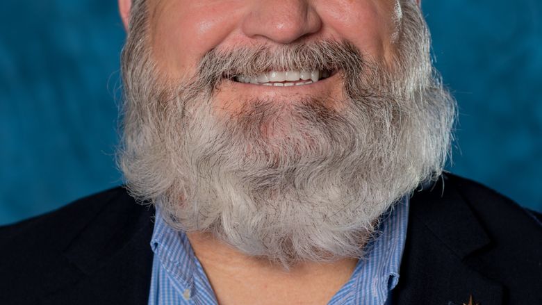 man with beard smiling in head shot