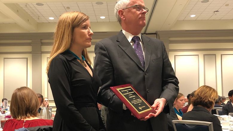 Woman receiving a plaque award from a man
