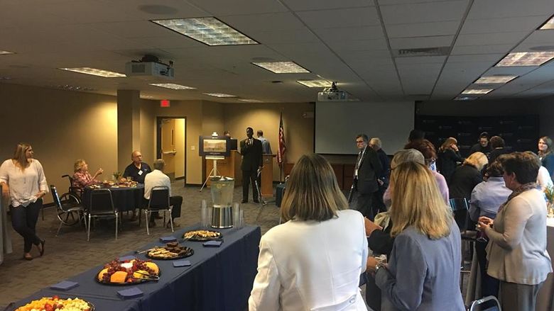 group of people in room listening to a speaker and enjoying cheese and fruit