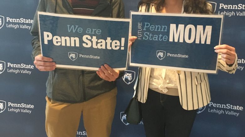 a young man and a woman who is his mom holding PSU signs