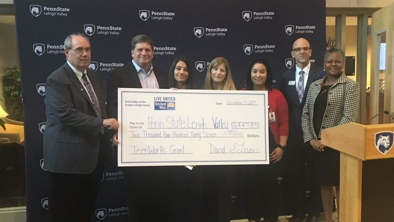 people standing with big check at presentation