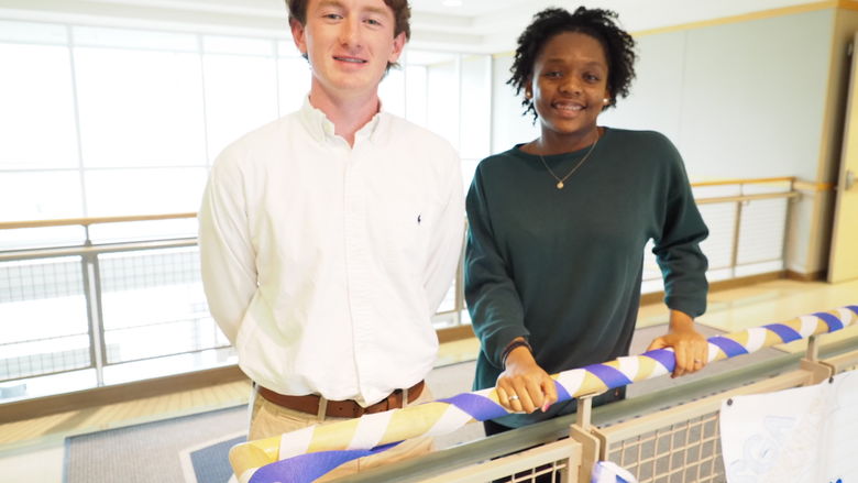 A male student and female student posing in a hallway