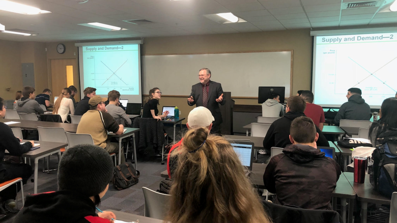 man standing in middle of classroom teaching