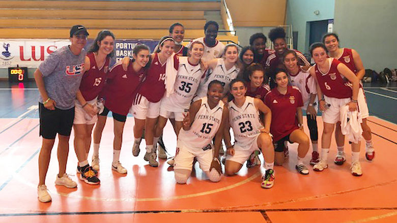 A group photo of women basketball players standing together on an indoor basketball court
