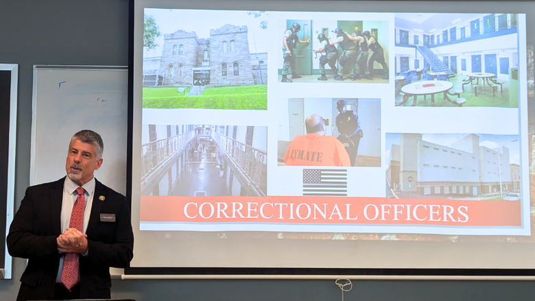 a corrections director speaks to a class of students in front of a powerpoint