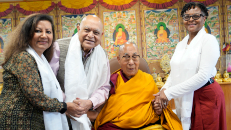 two women and a man smile next to the Dalai Lama 