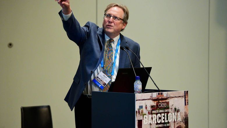 Professor Livert gesturing with his arm up during a lecture
