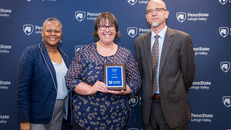 two women and a man posing with an award