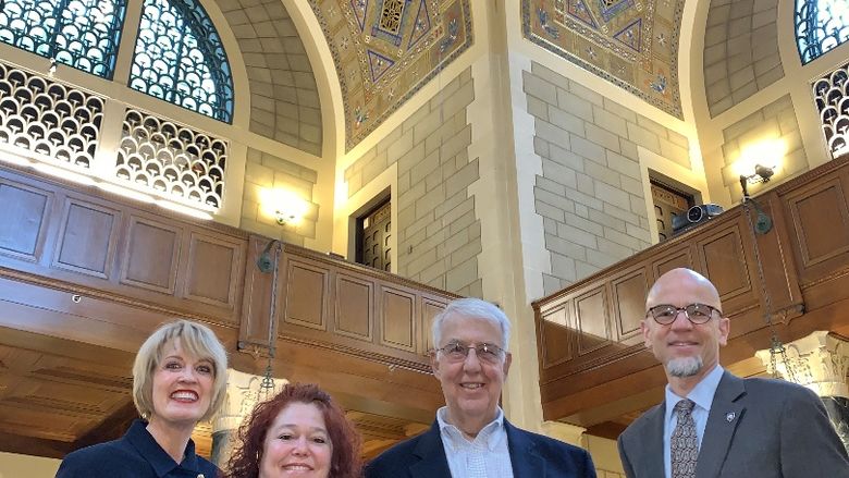 four people with decorative ceiling behind them
