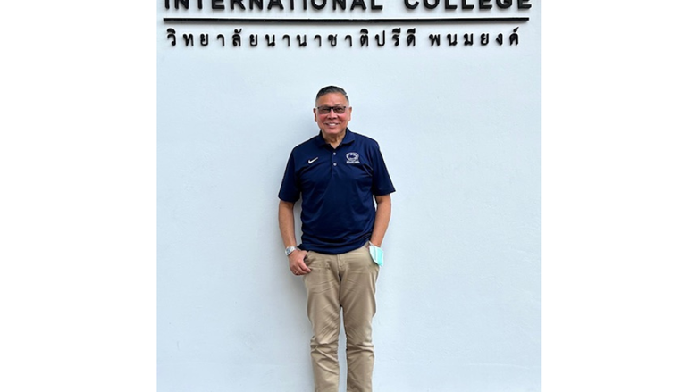 a man smiles in front of an international college 