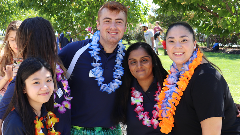 Four smiling students standing arm-in-arm.
