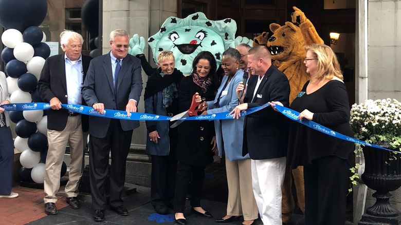 people cutting a blue ribbon with Nittany Lion