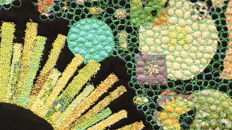 textile artwork showing a flower and green and blue shapes
