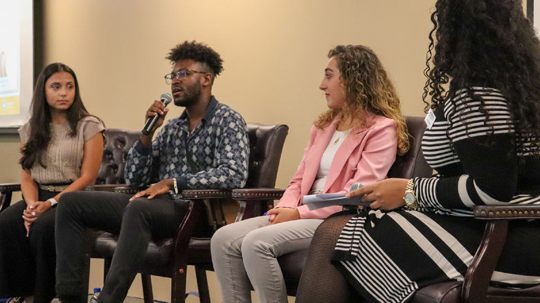 Three students on stage in panel setting