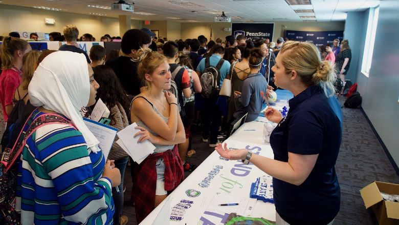 large group of students talking to club leaders at tables
