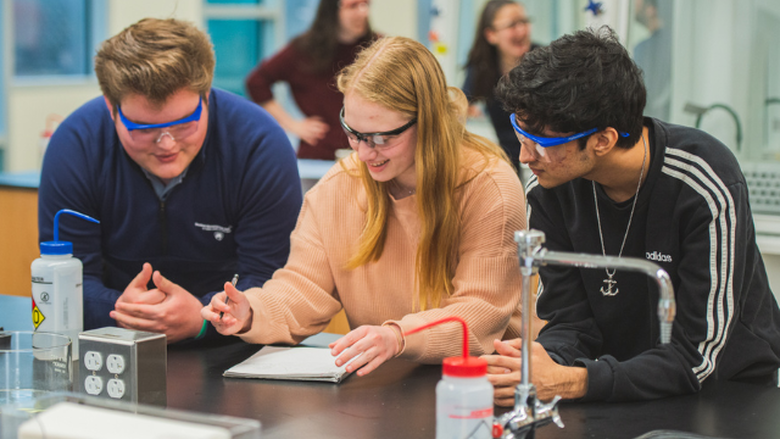 students examining a sample through a microscope