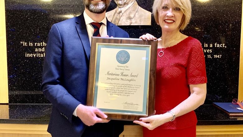 man handing framed award to woman