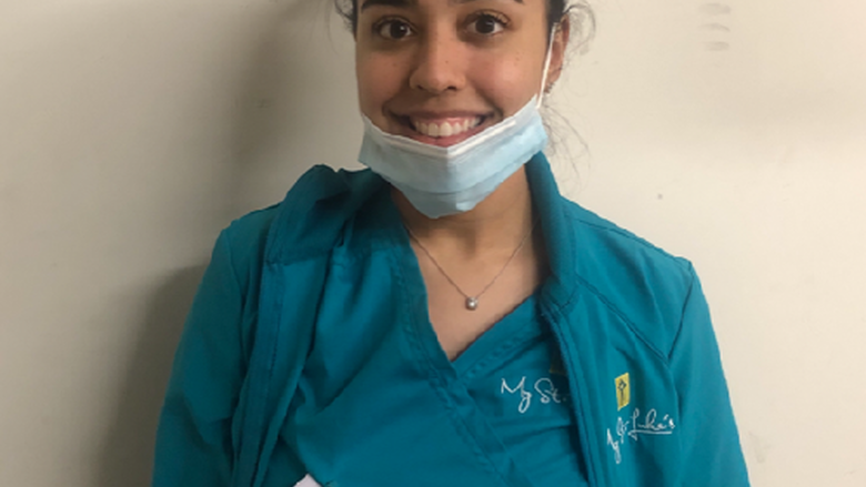 young woman wearing scrubs and with mask around her chin