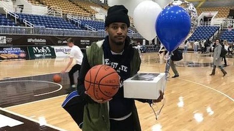 basketball player holding balloons and cake on court
