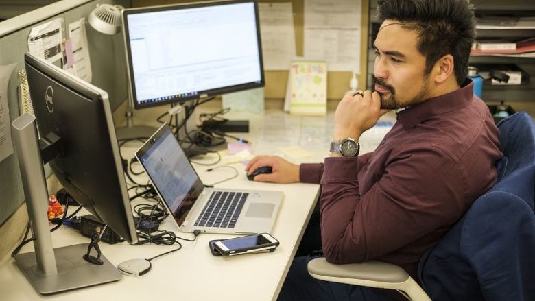 man sitting at desk staring at computer screen