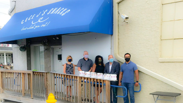 five people posed in front of a blue awning