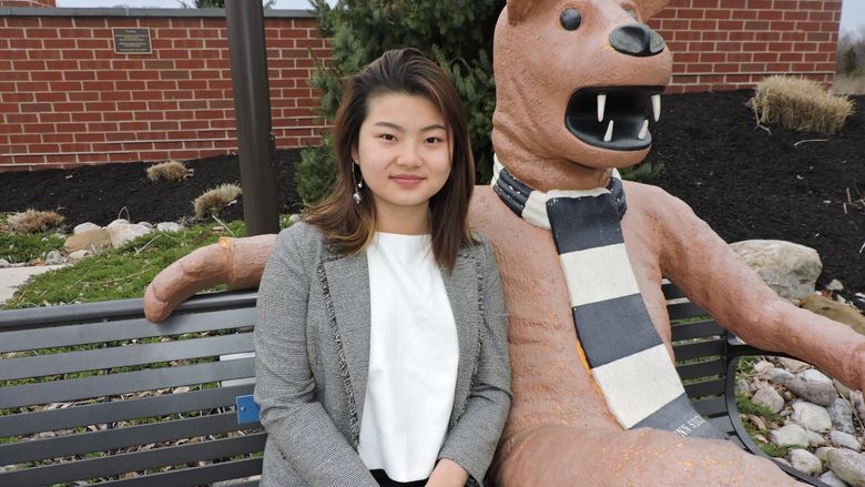 student sitting next to nittany lion statue