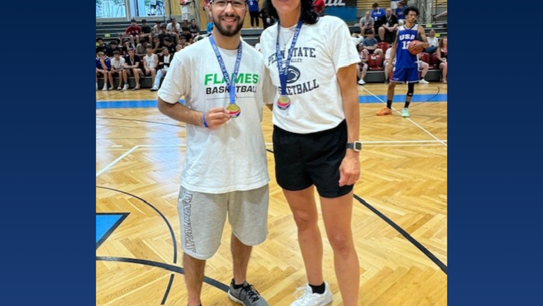 Two coaches smile on a basketball court