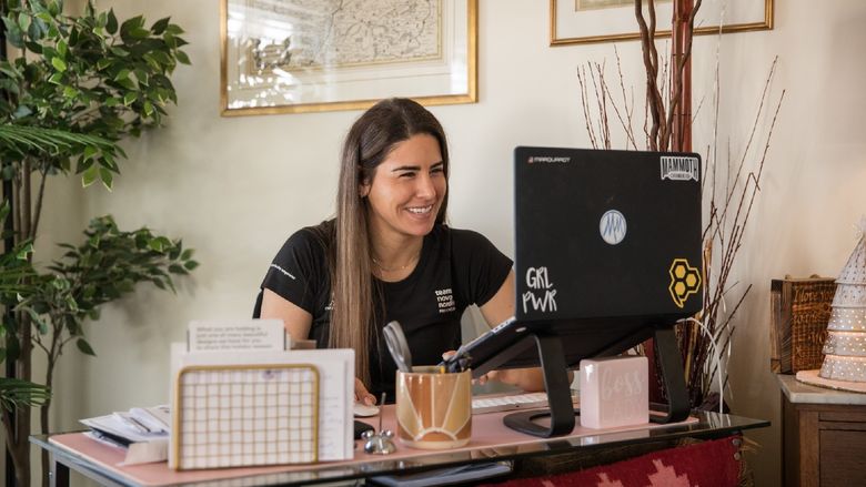 A woman sits at a desk and works on a laptop.