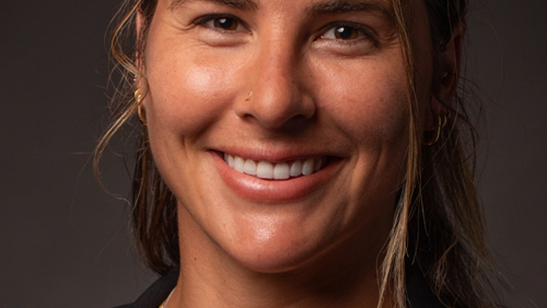 Woman with long brown hair looks at camera and smiles. 