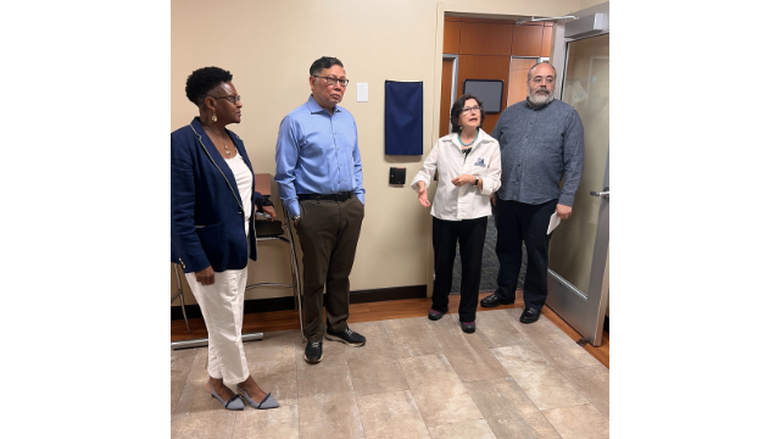 Faculty place a memorial plaque on the wall in remembrance of late professor
