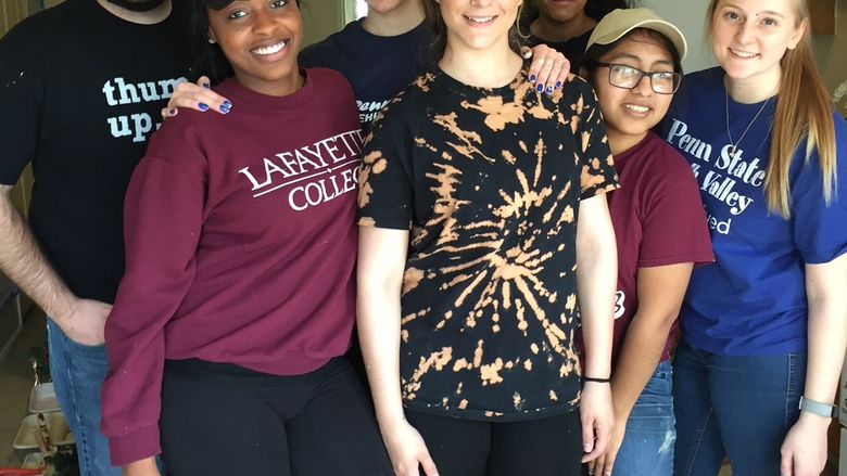 Group of students and staff member posing while volunteering