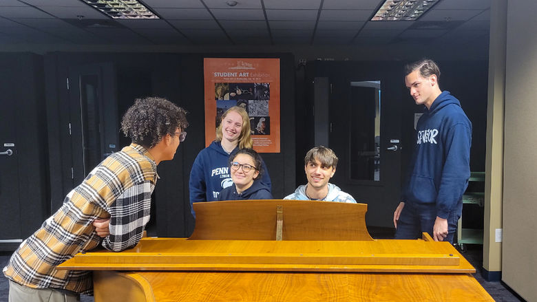 Penn State Lehigh Valley Students talking around the piano in campus music room