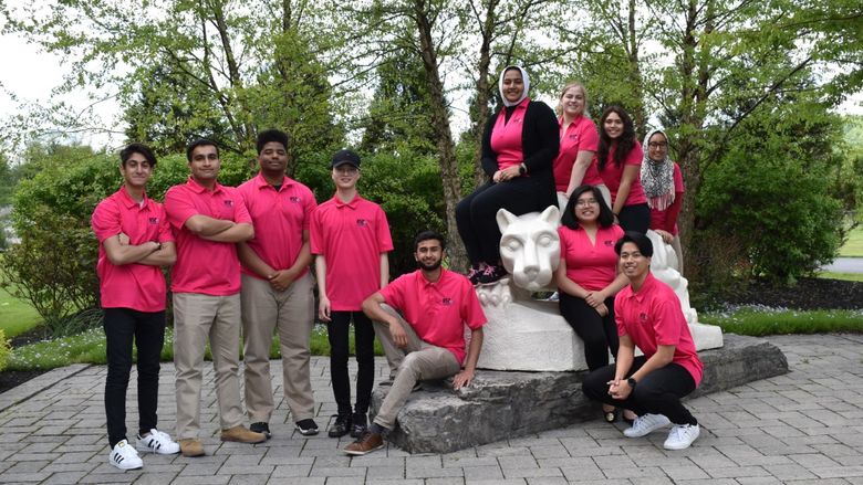 group of students standing by lion shrine 