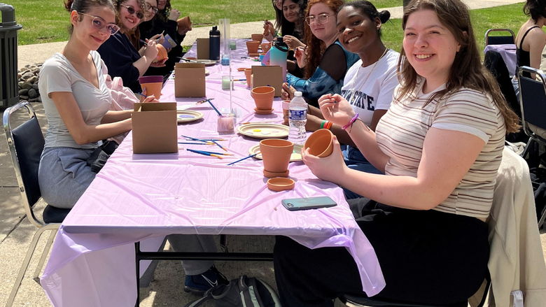 students paint flower pots outdoors 