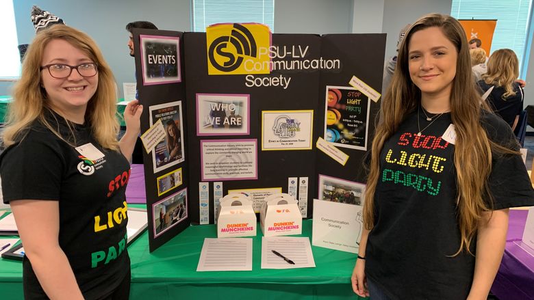 two students flanking a poster board tabletop presentation