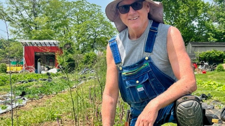 Professor Kevin Kelley smiling while kneeling in a garden