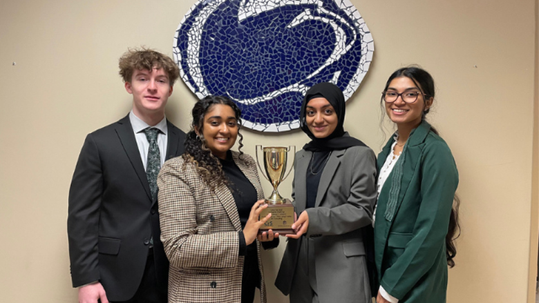 Students holding trophy in front of lion mosaic 