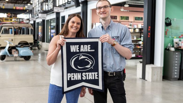 woman and man holding Penn State sign