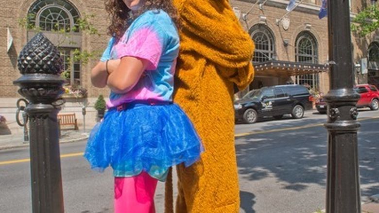 Young woman and Nittany Lion pose back to back in front of Hotel Bethlehem.