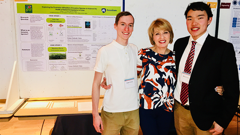 two male students and female professor in front of poster presentation